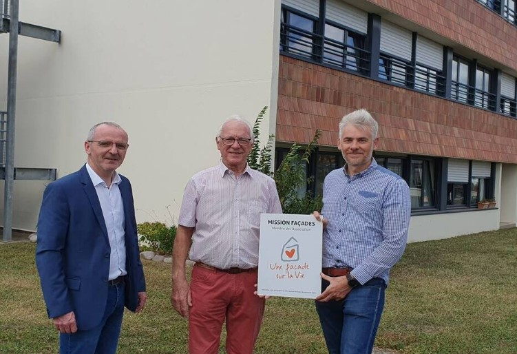 Trois personnes tenant une affiche "Une Façade sur la Vie".