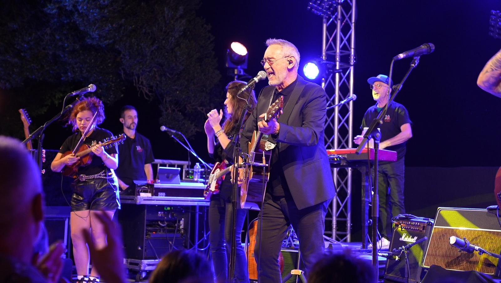 Un artiste chante en concert avec un groupe, une Façade sur la vie.